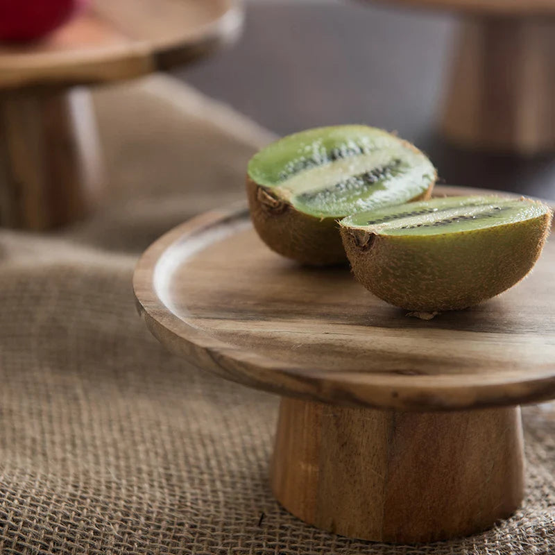 Oakline cake stand on a dining table showing natural wood base and glass dome