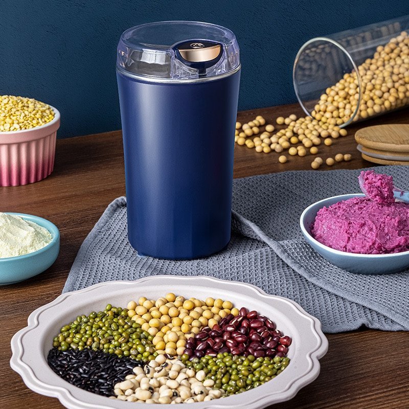Electric coffee grinder on a kitchen counter beside a bag of coffee beans